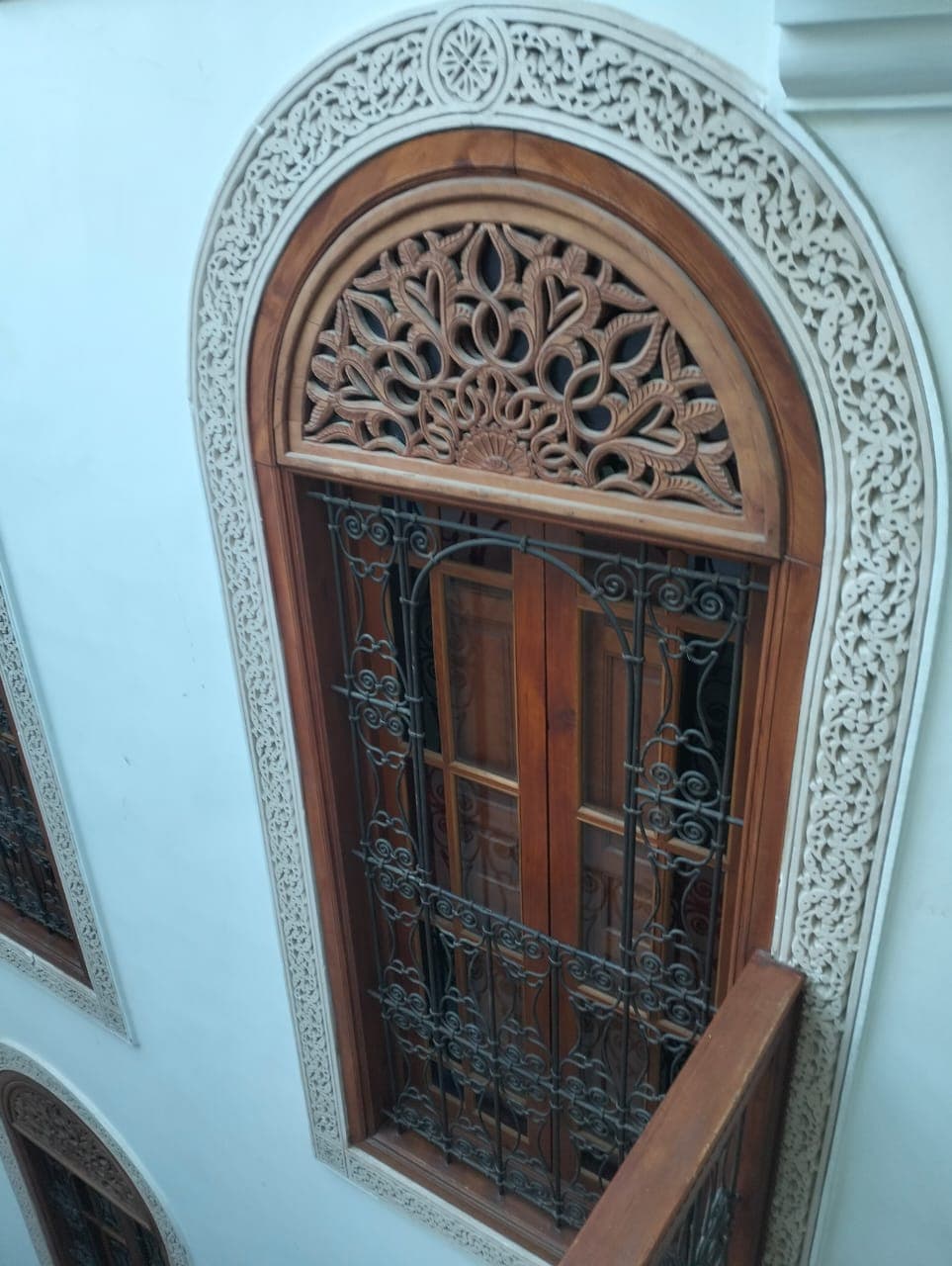 Fenêtre cintrée en bois de cèdre fabriquée à la main avec tympan floral ajouré, grille en fer forgé et cadre en plâtre sculpté